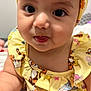 adorable, baby, cartoon_print, child, closeup, cute, expression, face, headband, indoor, infant, person, playful, portrait, sitting, skin, smiling, tongue, yellow_clothing, young_child
