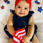 Eliana joined the competition — help win amazing prizes! baby, child, smile, red_bow, headband, flag, american_flag, bracelet, blue_dress, stars, sparkly, blanket, happy, cute, portrait, indoors, celebration, holiday, festive, person
