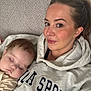 Lottie is registered to the contest to win money with this photo: woman, baby, sleeping, couch, hoodie, face, person, relaxing, indoor, closeup, casual_clothing, comfort, resting, portrait, head, brown_hair, skin, expression, young_child, family