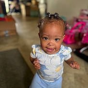 Marlaya is registered to the contest to win money with this photo: toddler, child, indoor, smiling, standing, braided_hair, floral_shirt, pants, happy, person, young_child, cute, playroom, toys, home, portrait, closeup, floor, bright, expression