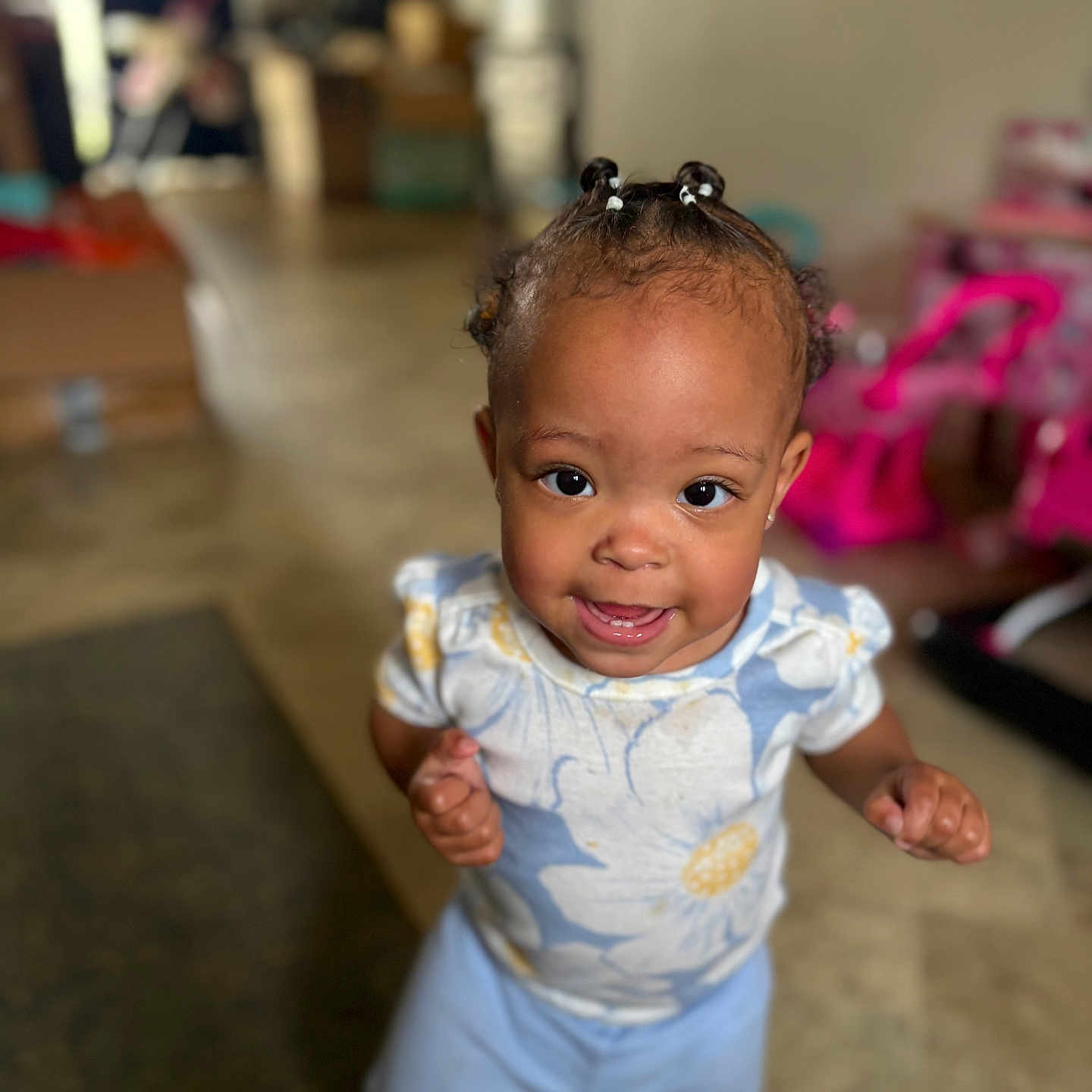Marlaya is registered to the contest to win money with this photo: braided_hair, bright, child, closeup, cute, expression, floor, floral_shirt, happy, home, indoor, pants, person, playroom, portrait, smiling, standing, toddler, toys, young_child