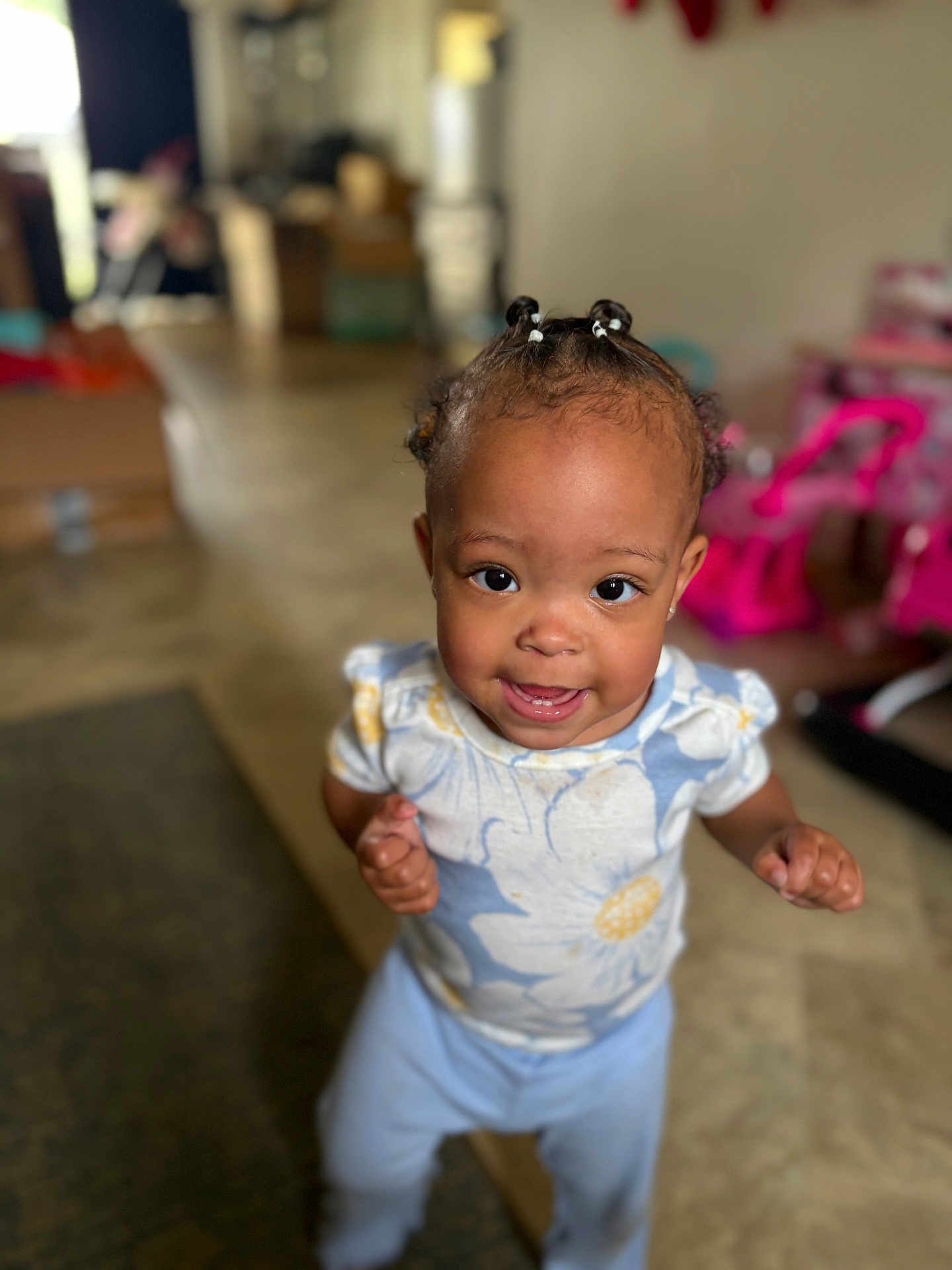 Marlaya is registered to the contest to win money with this photo: toddler, child, indoor, smiling, standing, braided_hair, floral_shirt, pants, happy, person, young_child, cute, playroom, toys, home, portrait, closeup, floor, bright, expression