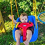 toddler, baby, swing, outdoor, grass, greenery, playground, child, seat, yellow_straps, red_plastic, blue_swing, barefoot, sunlight, nature, play, young_child, expression, summer, park