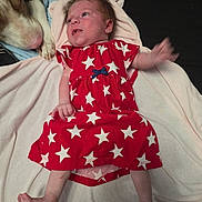 Phoenix joined the competition — help win amazing prizes! animal, baby, blanket, child, companion, curious, cute, dog, face, foot, hair, hand, indoor, infant, lying_down, pet, red_dress, skin, soft_lighting, stars