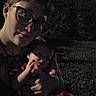 affection, baby, casual, child, closeup, dark, evening, face, family, glasses, grass, holding, human, love, night, outdoor, person, portrait, shadow, together