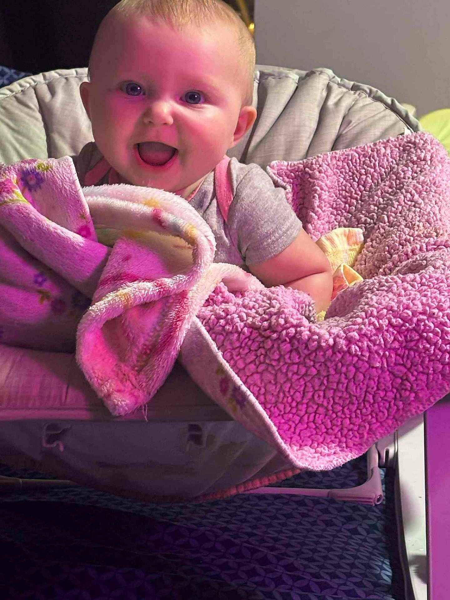 Aspen is registered to the contest to win money with this photo: baby, child, smiling, blanket, pink, cushion, chair, indoors, happy, face, clothing, person, cozy, soft, cute, infant, portrait, warm, comfort, seated