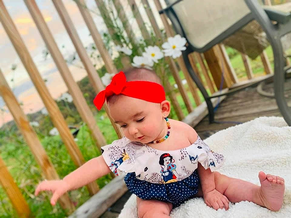 Madalynn is registered to the contest to win money with this photo: baby, baby_toddler_clothing, cap, child, eye, face, fence, fun, grass, happy, hat, head, headgear, headwear, leisure, pattern, person, plant, sitting, skin