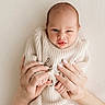 baby, infant, hands, knitted_sweater, cozy, cute, tongue_out, newborn, soft_light, portrait, human, skin, fingers, nails, holding, expression, face, small, warm, gentle