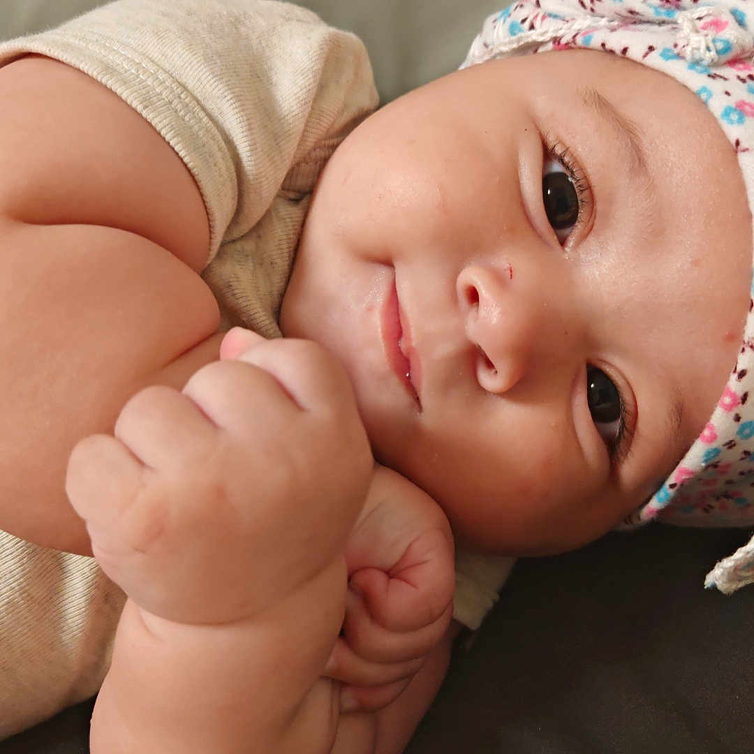 Hichem a rejoint le concours — aidez-le/la à gagner de superbes lots ! arm, baby, blanket, child, chubby, closeup, clothing, cute, expression, face, floral_pattern, hand, hat, indoor, infant, lying_down, portrait, skin, smile, soft_texture