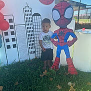 Mark is registered to the contest to win money with this photo: child, boy, grass, spiderman, cutout, cupcakes, balloons, outdoor, fence, cityscape, backdrop, shirt, shorts, barefoot, sunlight, shadow, party, decorations, trees, daytime