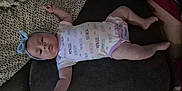 Maddie is registered to the contest to win money with this photo: baby, blanket, bow, calm, child, comfortable, couch, cute, dinosaur_pattern, face, headband, indoors, infant, lying_down, onesie, person, pillow, princess, resting, soft_toys