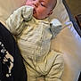 Maddie is registered to the contest to win money with this photo: baby, infant, onesie, pillow, blanket, lying_down, indoors, person, face, hand, footwear, soft_fabric, cozy, resting, newborn, cute, child, sleepwear, comfort, young