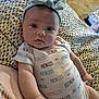 Maddie is registered to the contest to win money with this photo: arm, baby, bow, closeup, curious, cute, face, floor, hand, headband, indoors, infant, lying_down, onesie, patterned_blanket, person, princess, soft_lighting, stone_floor, young_child