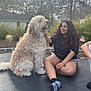 Drew joined the competition — help win amazing prizes! dog, person, outdoor, trampoline, smiling, curly_hair, petting, sitting, casual_clothing, house, trees, cloudy_sky, nature, friendship, animal, leisure, daytime, happy, relaxed, yard