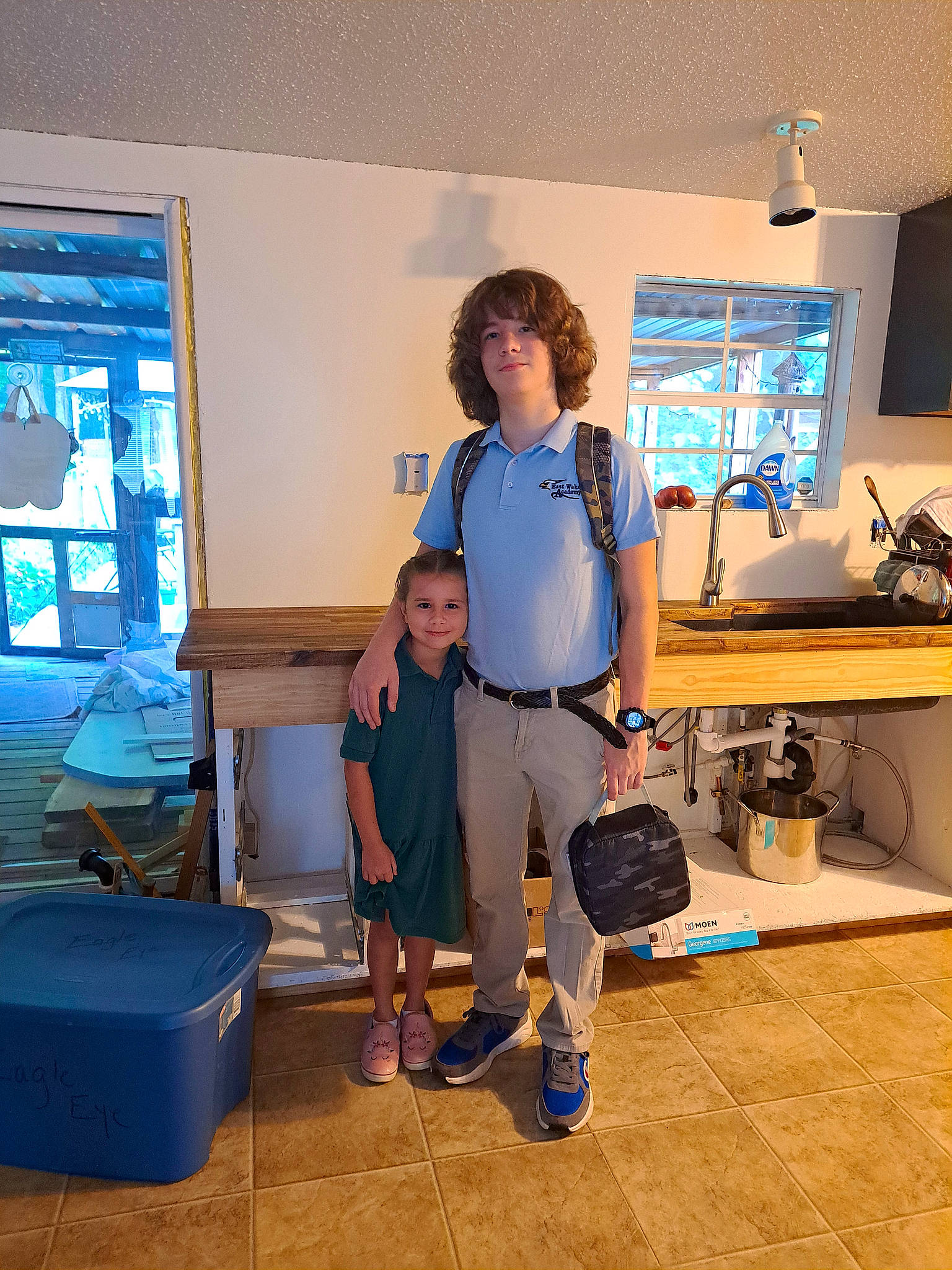 Ashlynn is registered to the contest to win money with this photo: backpack, bag, boot, desk, event, flooring, fun, hardwood, home_appliance, houseplant, joy, leisure, luggage_and_bags, machine, person, room, shorts, standing, t_shirt, table