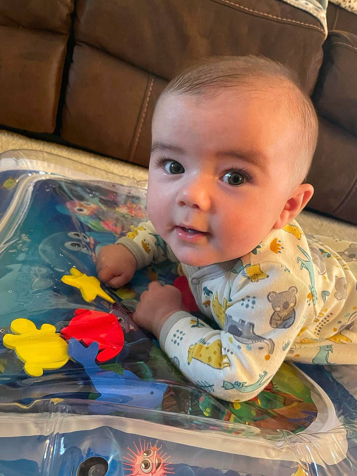 Kasey is registered to the contest to win money with this photo: baby, baby_toddler_clothing, cheek, child, comfort, eye, facial_expression, flooring, fun, happy, head, iris, mouth, nose, person, sitting, skin, smile, toddler, toy