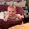 Jdee is registered to the contest to win money with this photo: baby, child, smiling, playpen, indoor, person, happy, face, hand, skin, furniture, fabric, tooth, head, room, blurred_background, standing, holding, cushion, blanket