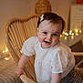 Mia participe au concours pour gagner de l'argent avec cette photo : baby, casual_clothing, cheerful, child, cozy, cute, face, fairy_lights, furniture, hair_clip, happy, indoors, portrait, smile, soft_focus, toddler, warm_lighting, white_shirt, wicker_chair, young_child