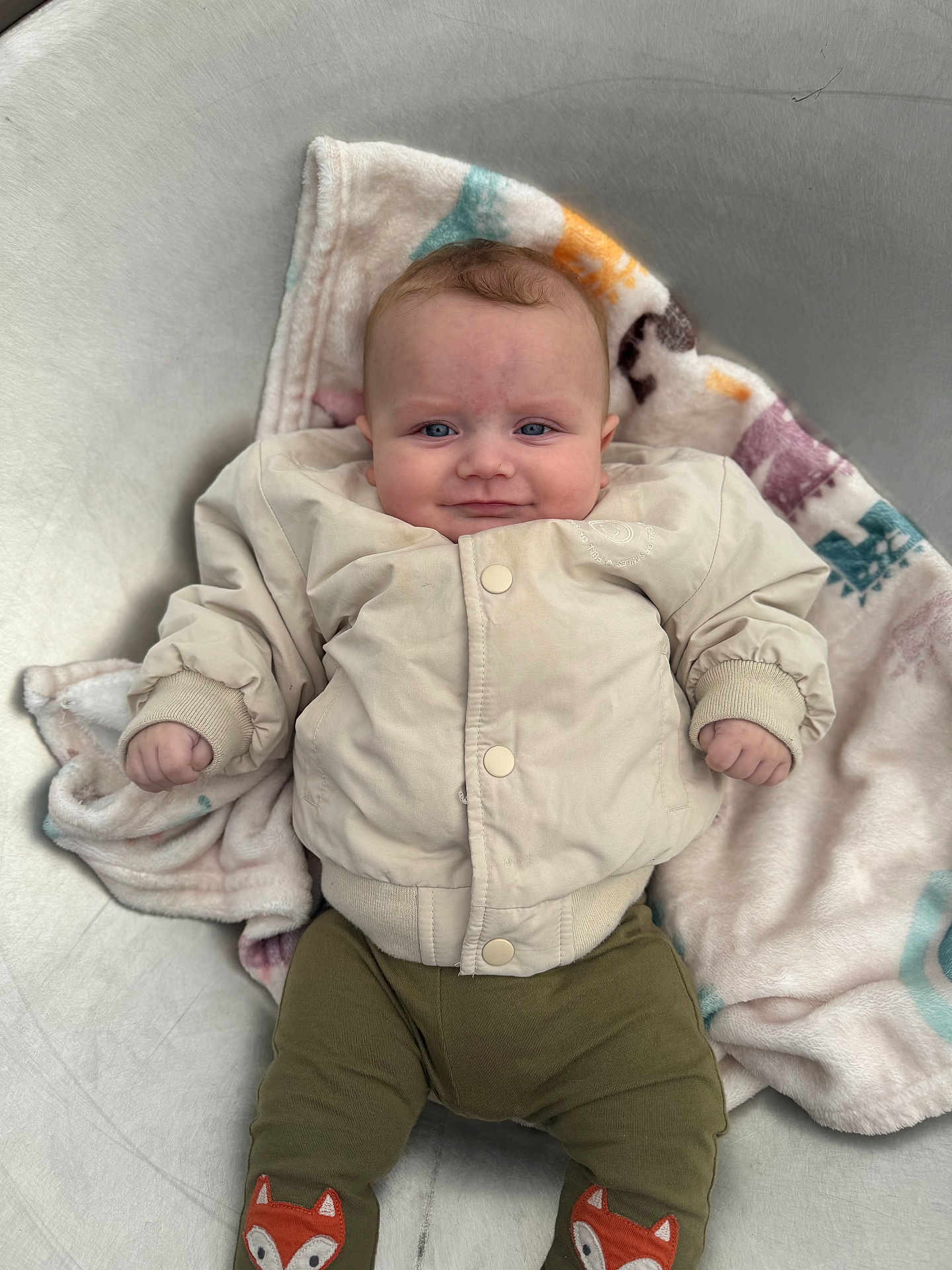 Arlen-Ray is registered to the contest to win money with this photo: baby, infant, blanket, jacket, pants, fox_patch, metallic_tub, clothing, cute, lying_down, smile, face, hand, footwear, soft_texture, indoors, child, person, portrait, cozy
