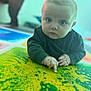 baby, blue_eyes, child, closeup, colorful, crawling, curious, cute, floor, hands, indoor, infant, long_sleeve, pattern, person, playmat, pointing, portrait, soft_focus, young