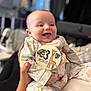 animal_print, baby, badge, blurred_background, child, clothing, cute, face, giraffe, hand, happy, holding, indoor, infant, newborn, onesie, pattern, person, smiling, soft