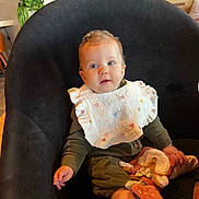 Anastasia a rejoint le concours — aidez-le/la à gagner de superbes lots ! baby, child, bib, chair, soft_toy, indoor, plant, wooden_furniture, curious, cute, sitting, clothing, face, person, portrait, cozy, warm_colors, expression, head, sock