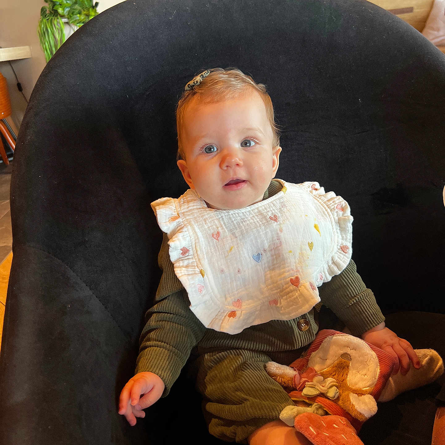 Anastasia a rejoint le concours — aidez-le/la à gagner de superbes lots ! baby, child, bib, chair, soft_toy, indoor, plant, wooden_furniture, curious, cute, sitting, clothing, face, person, portrait, cozy, warm_colors, expression, head, sock