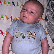 Westen is registered to the contest to win money with this photo: baby, bird_pattern, blanket, blue_shirt, child, comfortable, curious_expression, cute, family_theme, human, indoors, infant, lying_down, pajamas, portrait, printed_shirt, sleepwear, soft_lighting, text_on_clothing, young_child