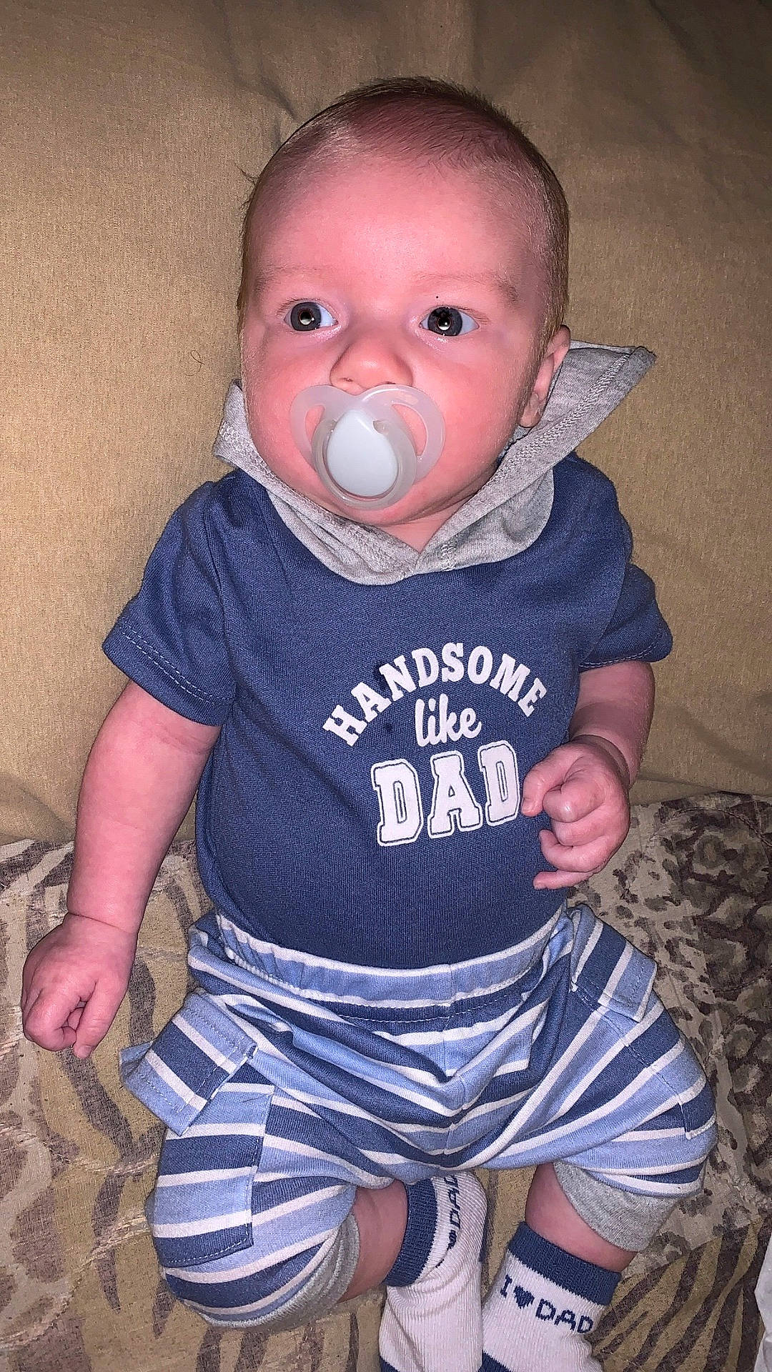 Westen joined the competition — help win amazing prizes! baby, blue_shirt, casual, child, clothing, comfortable, cute, face, hands, indoor, infant, pacifier, patterned_surface, person, portrait, sitting, socks, striped_pants, text_on_clothing, young