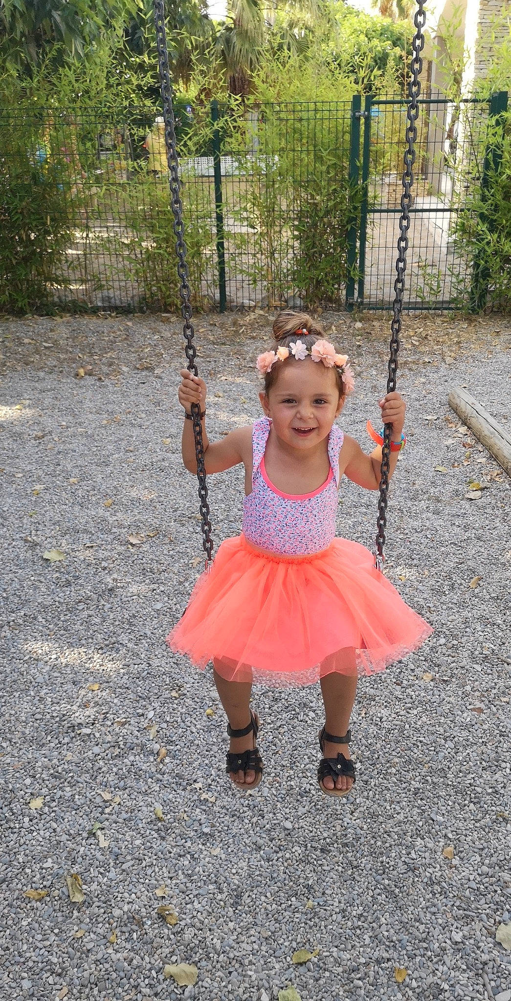 Inaya participe au concours pour gagner de l'argent avec cette photo : baby_toddler_clothing, child, city, eye, fashion_accessory, fence, fun, grass, happy, joy, leisure, magenta, pattern, person, pink, plant, recreation, smile, standing, swing