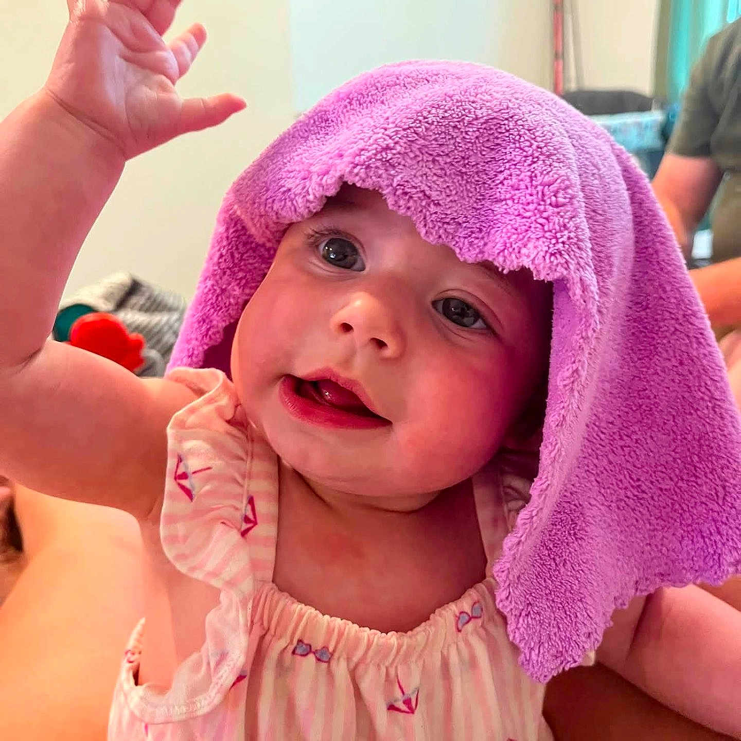 Madelynn is registered to the contest to win money with this photo: baby, child, towel, purple, raising_hand, cute, indoor, person, smiling, face, clothing, pink, playful, portrait, infant, skin, hand, expression, young, happy