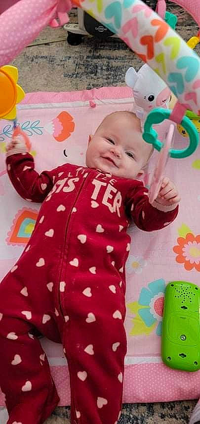 Abby is registered to the contest to win money with this photo: baby, baby_playing_with_toys, baby_products, baby_toddler_clothing, child, comfort, face, facial_expression, happy, head, mammal, pattern, people, person, pink, product, skin, sleeve, smile, textile