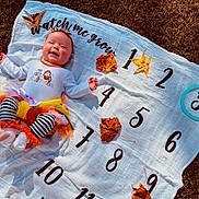 Weslynne joined the competition — help win amazing prizes! baby, infant, smiling, halloween, costume, striped_clothing, headband, blanket, numbers, leaves, autumn, grass, outdoor, tutu, white_blanket, celebration, seasonal, cute, child, happy