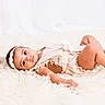baby, infant, child, lying_down, fluffy_rug, cream_outfit, headband, lace, soft_toys, pastel_colors, cute, portrait, indoor, looking_at_camera, small_feet, peaceful, adorable, young_child, soft_lighting, cozy