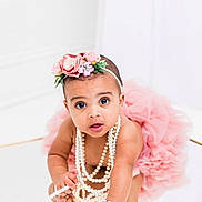 Delilah is registered to the contest to win money with this photo: accessory, adorable, baby, child, closeup, crawling, curious, cute, fashion, flower, headband, infant, jewelry, pearl_necklace, pink_tutu, playful, portrait, reflection, studio, white_background