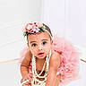 baby, child, pearl_necklace, pink_tutu, headband, flower, reflection, cute, portrait, infant, studio, white_background, jewelry, curious, crawling, closeup, adorable, fashion, accessory, playful