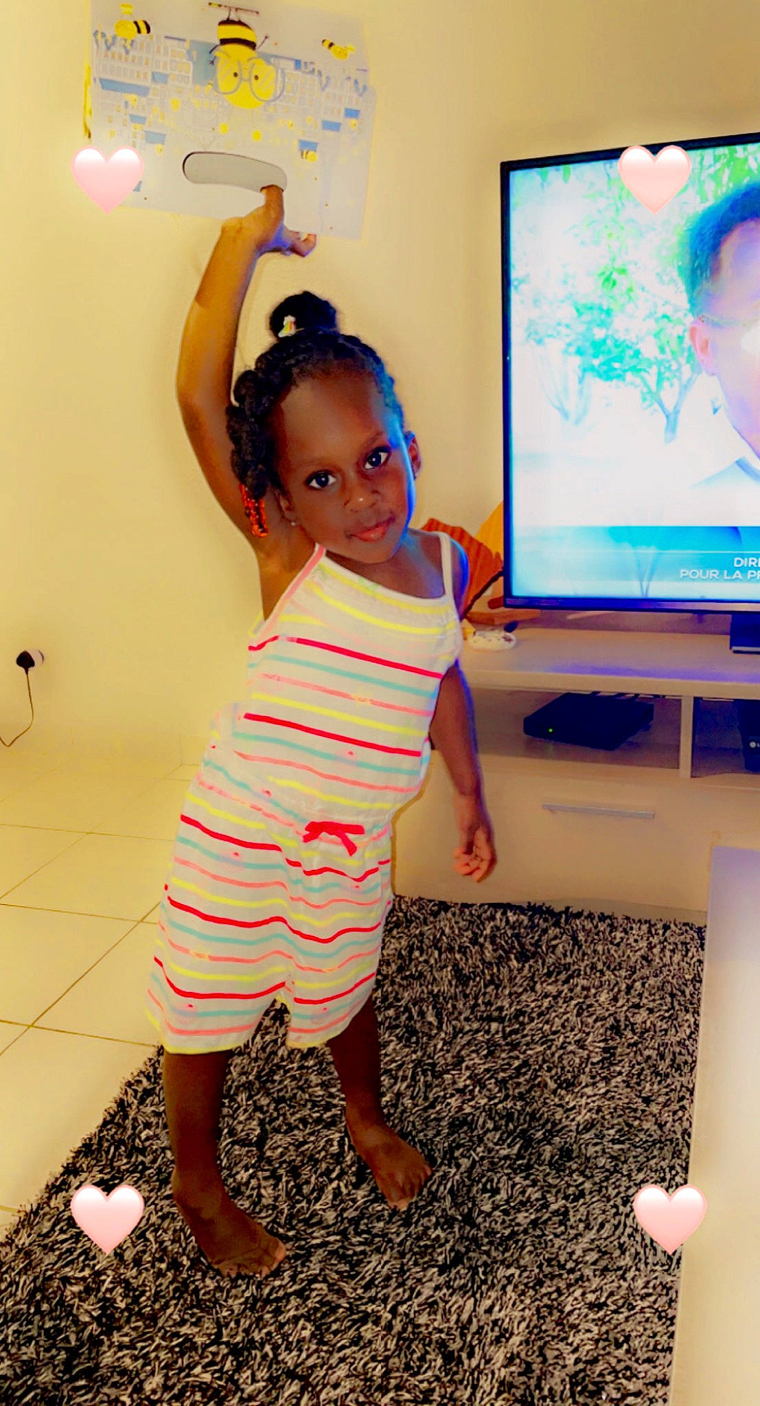 Chrislene a rejoint le concours — aidez-le/la à gagner de superbes lots ! baby_toddler_clothing, child, finger, flat_panel_display, flooring, fun, gesture, hairstyle, happy, human_leg, joint, output_device, person, pink, shoulder, smile, standing, television, television_set, thigh