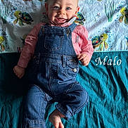 Malo participe au concours pour gagner de l'argent avec cette photo : baby, denim_overalls, pink_shirt, smiling, lying_down, blanket, sea_turtles, cute, child, infant, happy, blue_eyes, bare_feet, fabric, pattern, playful, portrait, indoors, clothing, colorful