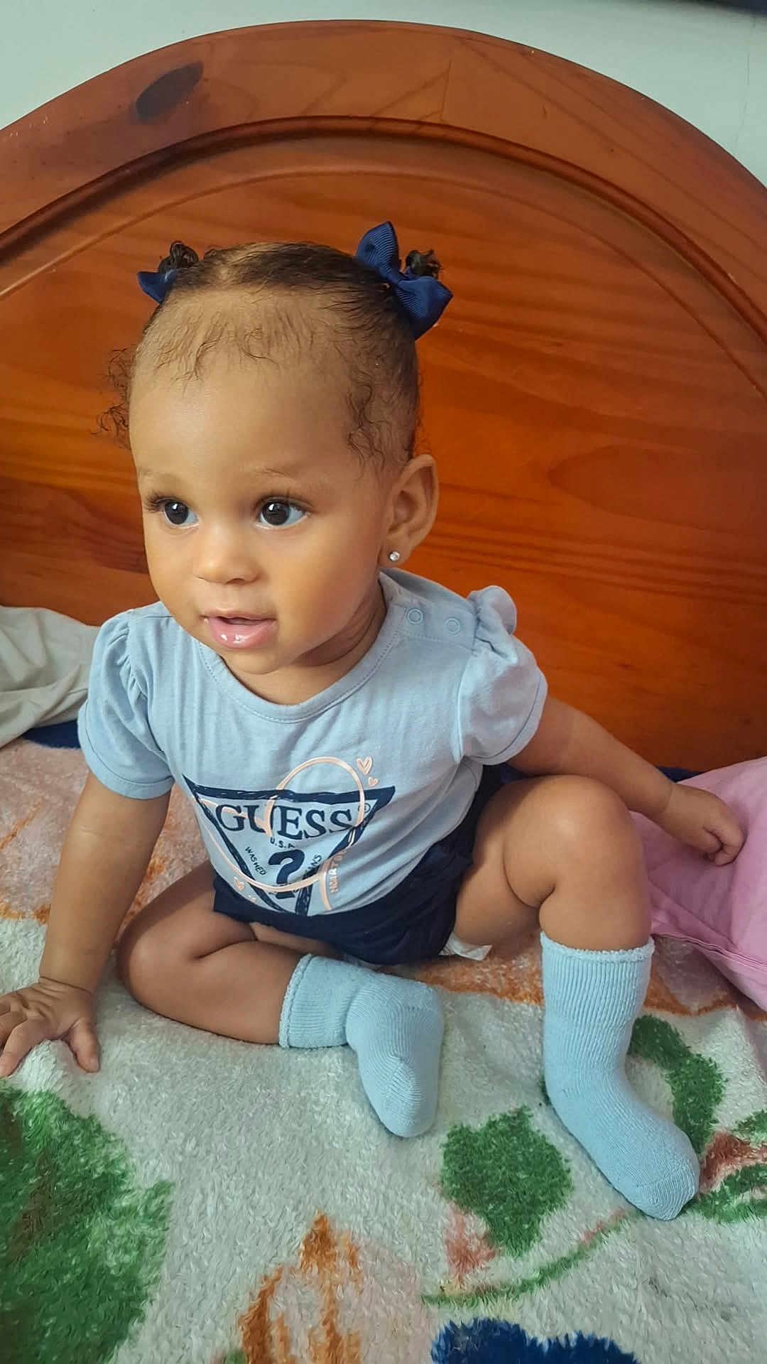 Luna a rejoint le concours — aidez-le/la à gagner de superbes lots ! child, baby, toddler, sitting, bed, blanket, socks, hair_bows, earrings, headboard, wooden_headboard, big_eyes, onesie, clothing, indoor, portrait, smile, hand, skin, curious