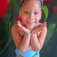 Lyana a rejoint le concours — aidez-le/la à gagner de superbes lots ! child, smiling, tiara, crown, bracelet, blue_swimsuit, swimsuit, portrait, playful_pose, standing, colorful_wall, mural, earrings, beaded_necklace, hands_under_chin, young_child, hair_bun, indoor, tile_floor, happy