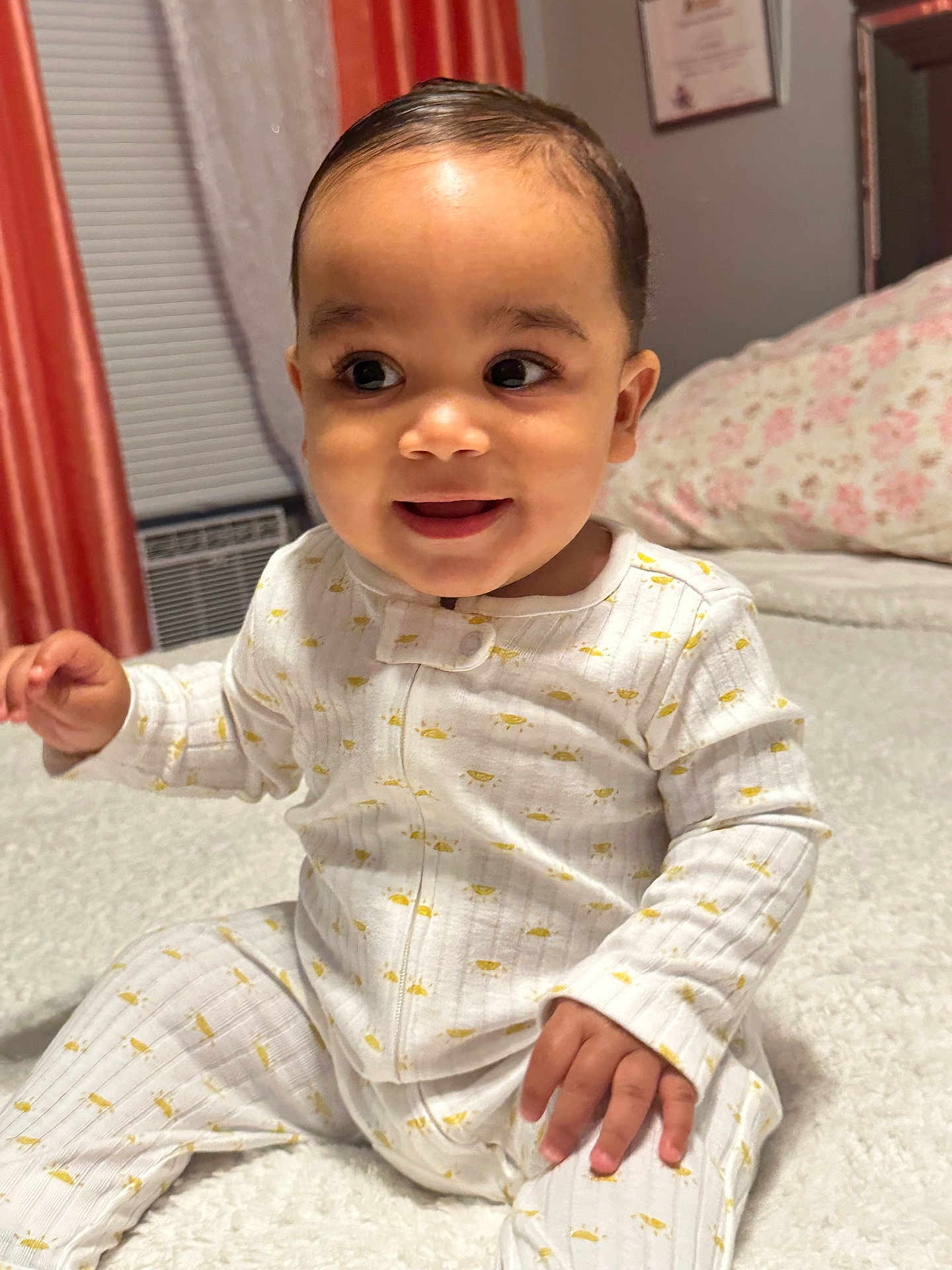 Jaylen Aviles is registered to the contest to win money with this photo: baby, child, pajamas, smile, indoor, bedroom, blanket, soft, curly_hair, cute, infant, happy, sitting, face, person, cozy, young, portrait, home, sleepwear