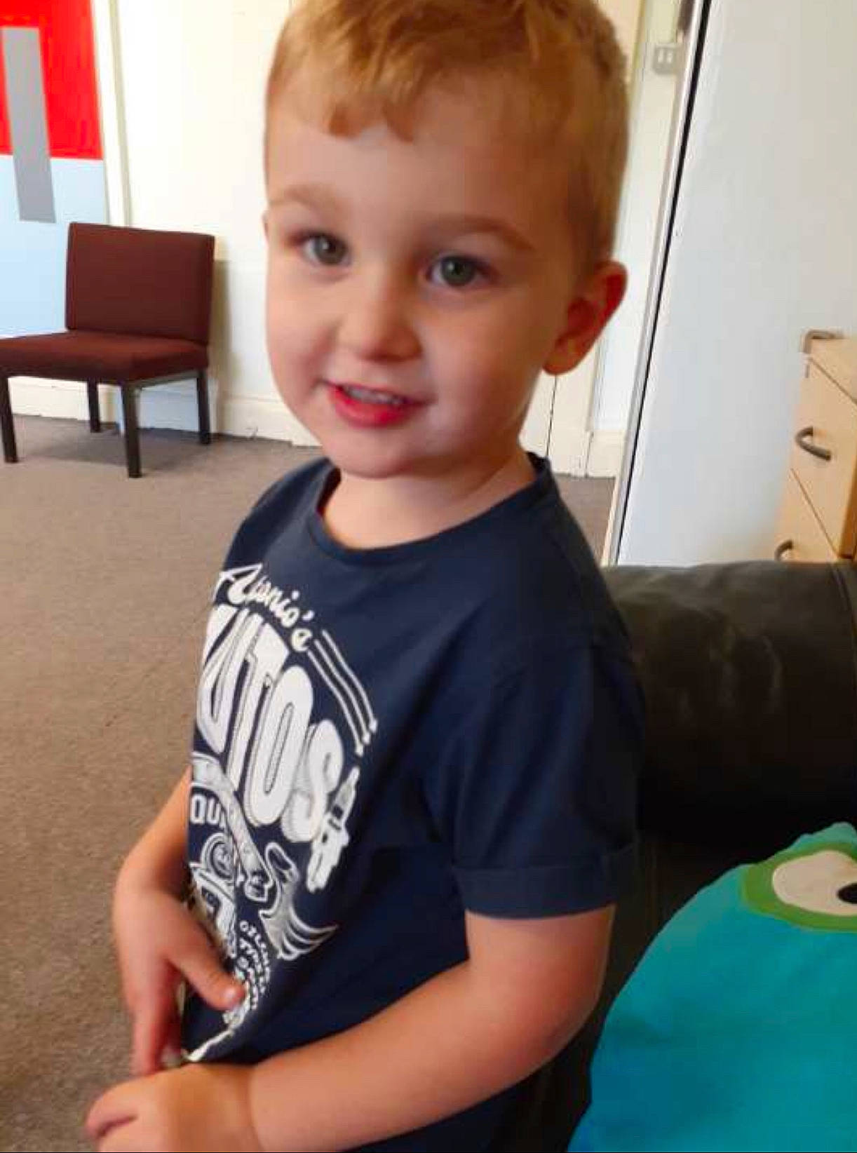 Deacon is registered to the contest to win money with this photo: arm, baby, cheek, child, chin, cool, face, forehead, hair, hairstyle, head, joint, neck, person, play, shoulder, skin, smile, standing, t_shirt