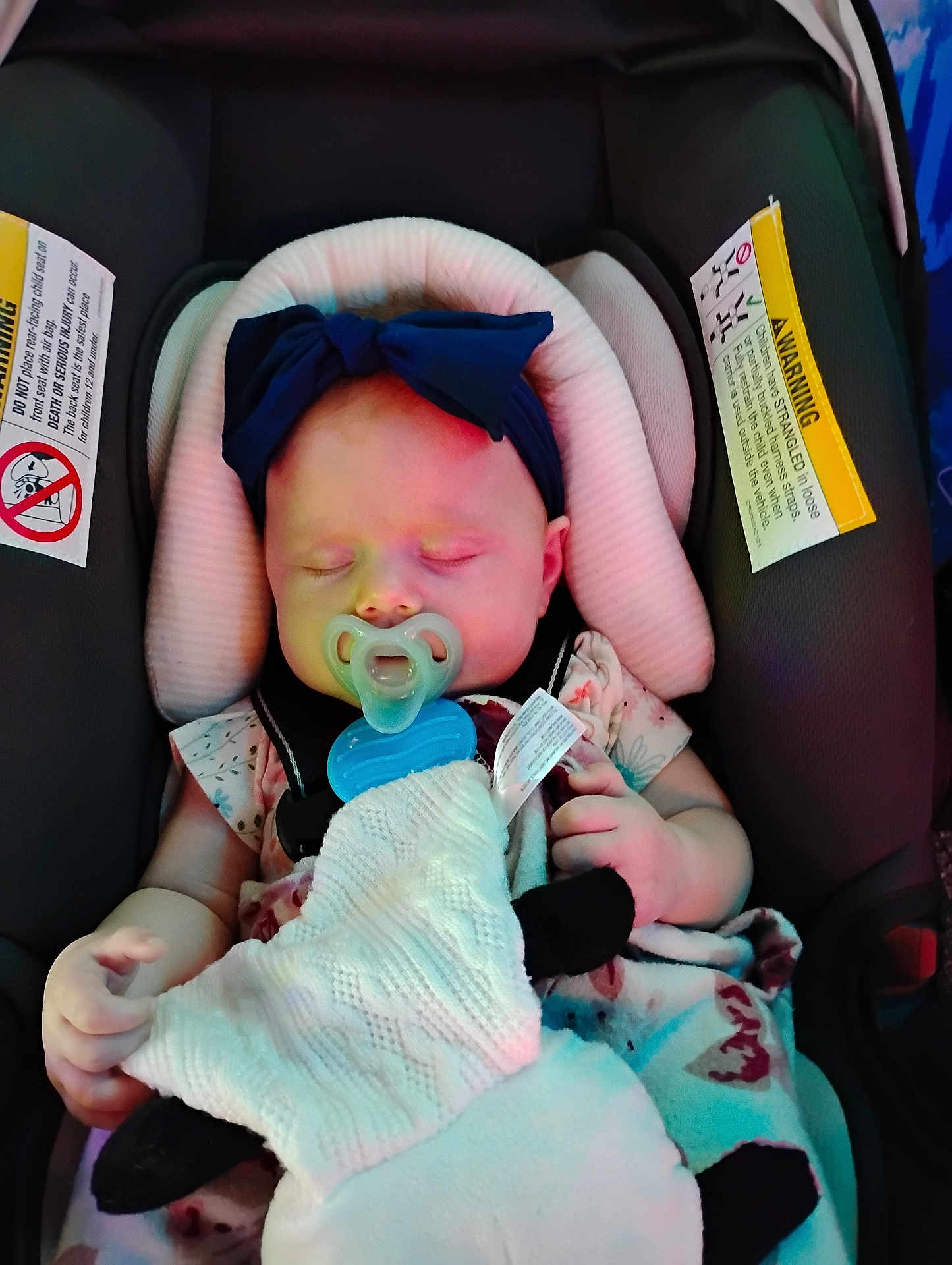 Macie is registered to the contest to win money with this photo: baby, sleeping, pacifier, car_seat, blanket, headband, infant, child, cute, resting, safety, warning_label, clothing, soft, peaceful, indoors, person, small_hand, comfort, adorable