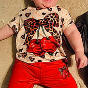 Stella joined the competition — help win amazing prizes! baby, child, smiling, laughing, red_pants, shirt, cherries, leopard_print, bow, happy, cute, infant, lying_down, clothing, texture, indoor, person, toddler, face, joyful
