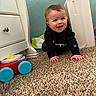 baby, child, crawling, carpet, toy, hoodie, smiling, indoor, furniture, dresser, blanket, happy, person, face, blue_eyes, floor, room, plush, clothing, cute