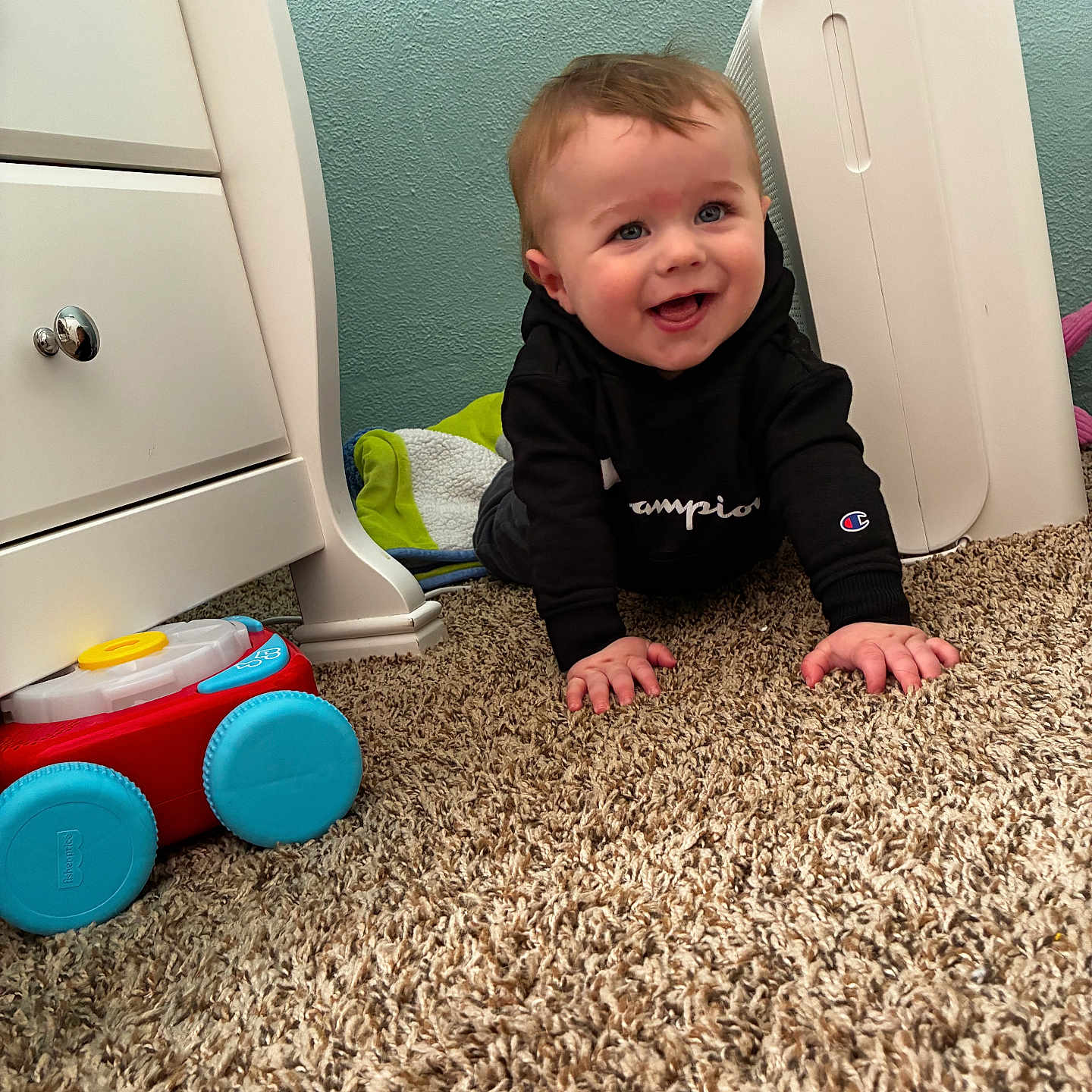 Zain joined the competition — help win amazing prizes! baby, child, crawling, carpet, toy, hoodie, smiling, indoor, furniture, dresser, blanket, happy, person, face, blue_eyes, floor, room, plush, clothing, cute