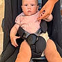 baby, child, stroller, infant, hand, adult_hand, pink_shirt, baby_seat, safety_belt, curious, skin, face, legs, outdoor, holding_hand, closeup, child_seat, expression, person, young