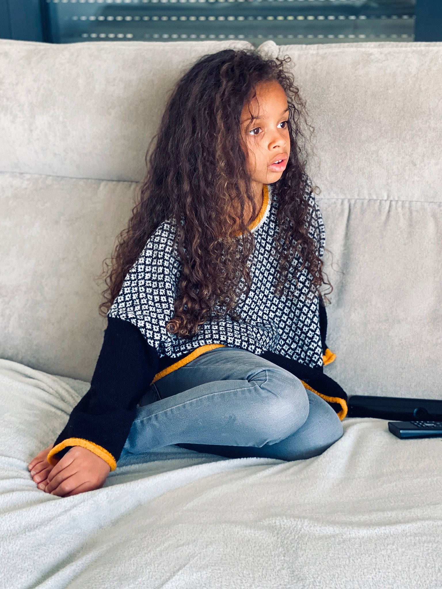 Inaya participe au concours pour gagner de l'argent avec cette photo : barefoot, black_hair, foot, furniture, jeans, knee, leg, linens, long_hair, person, pillow, room, sitting, sportswear, textile, thigh