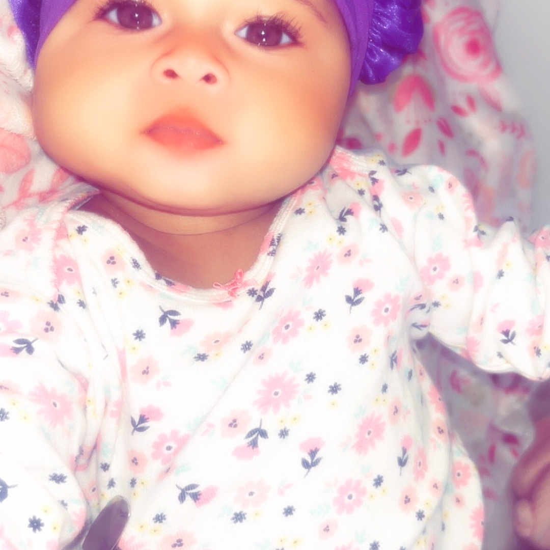 Kamiya joined the competition — help win amazing prizes! baby, infant, child, portrait, face, eyes, looking_at_camera, purple_bonnet, headwear, floral_clothing, onesie, pink, purple, blanket, bedding, indoors, close_up, sitting, cozy, photograph
