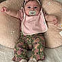 adorable, baby, bed, bib, child, comfortable, cushion, cute, embroidery, floral_pants, headband, indoor, infant, pacifier, person, pink, seated, smiling_eyes, socks, soft_texture